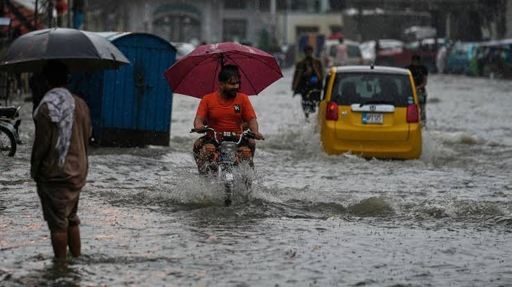 Flooded street in Lahore after heavy monsoon rainfall with vehicles moving through standing water.